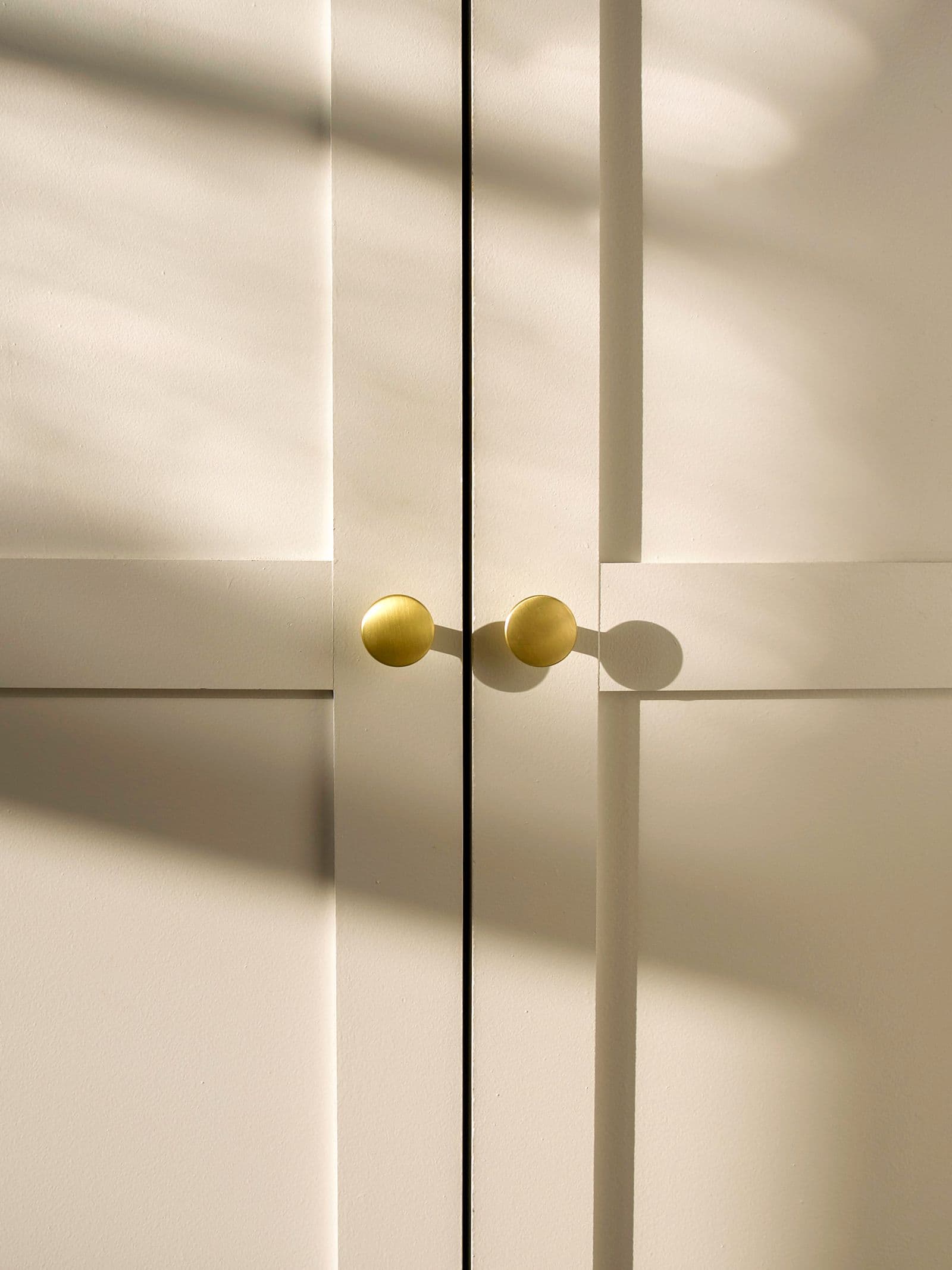 Detalle de tiradores de latón sobre puertas claras, luz natural