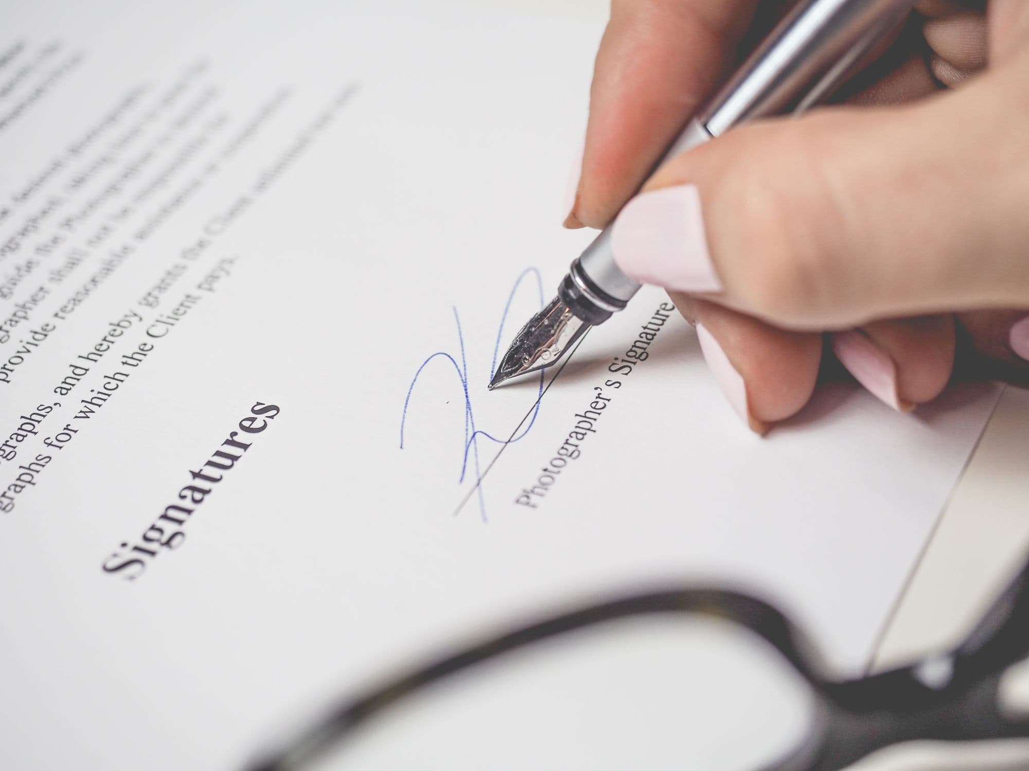 Mano firmando un documento con pluma estilográfica, primer plano