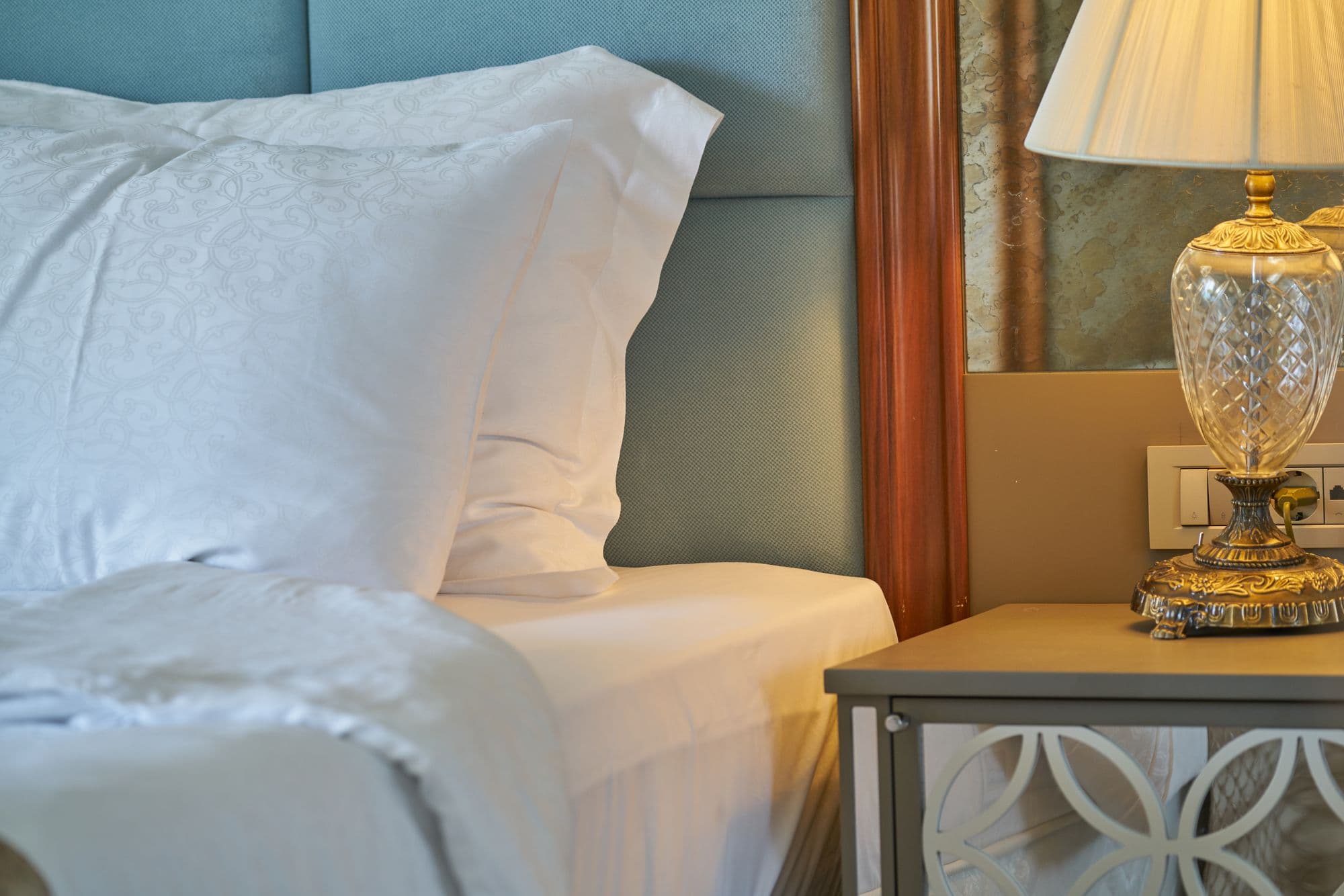 Detalle de una habitación de hotel, ropa de cama blanca y lámpara, luz cálida