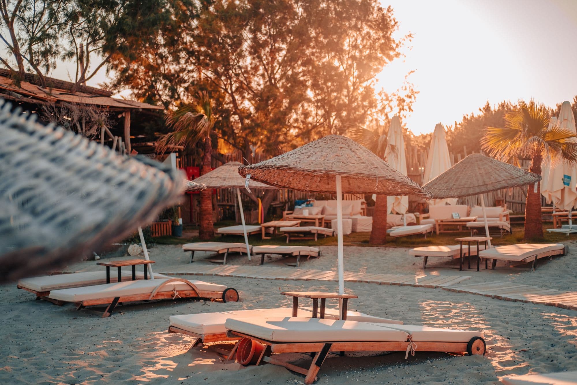 Beach club en la hora dorada, hamacas y sombrillas de paja
